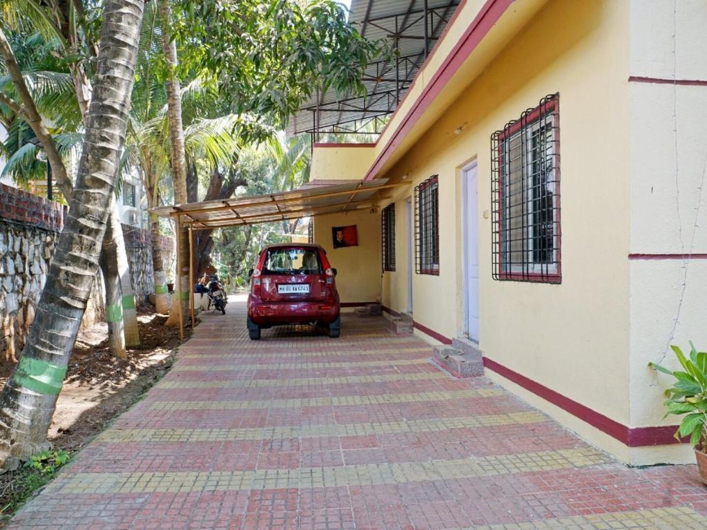 una piccola auto rossa parcheggiata accanto a un edificio di MM Cottage Near Mandir Road ad Alibaug