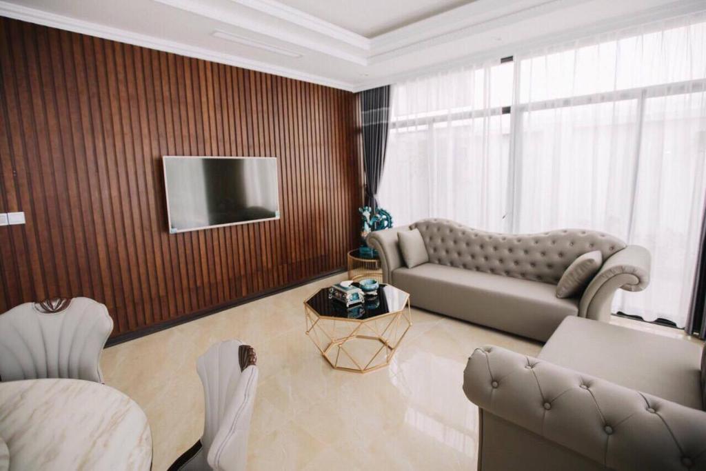 ein Wohnzimmer mit einem Sofa und einem TV in der Unterkunft FLC Villa Hạ Long 5 Phòng Ngủ in Hạ Long