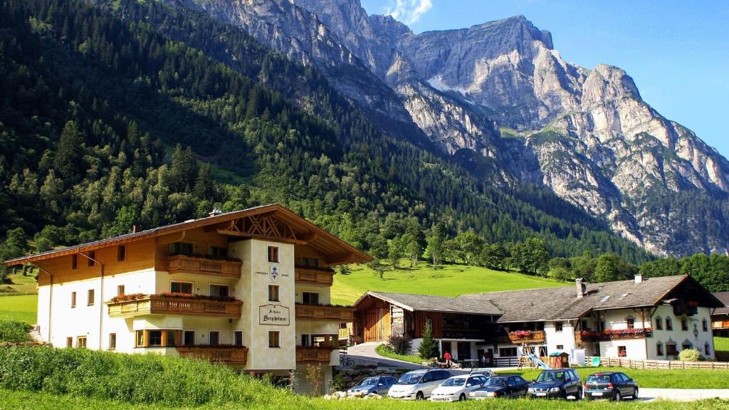 a hotel with cars parked in front of a mountain at Alfaierhof-Bergheimat in Gschnitz