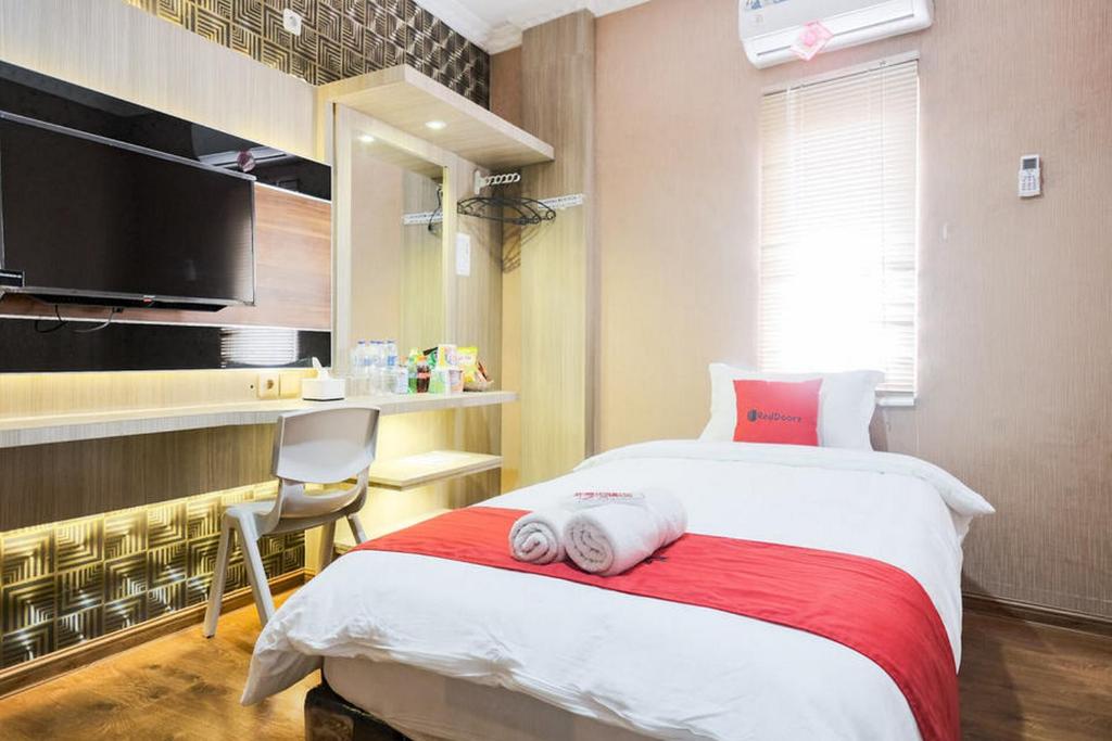 a bedroom with a bed with a chair and a tv at RedDoorz Plus @ Simpang USU Medan in Medan