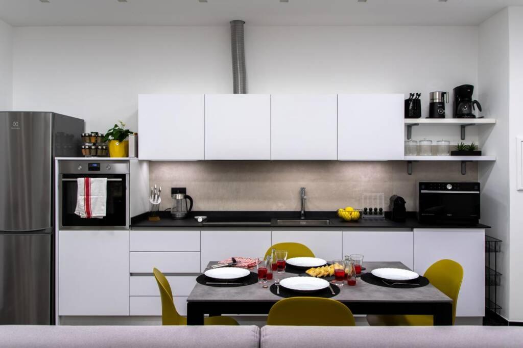 a kitchen with white cabinets and a table and chairs at LargoDoria - ViaArchivolto, box auto privato incluso in Albenga