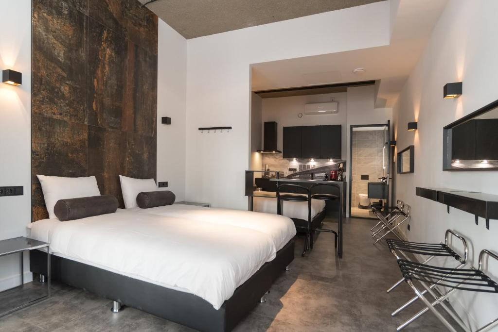 a bedroom with a large bed and a kitchen at Midtown Hotel Rotterdam in Rotterdam