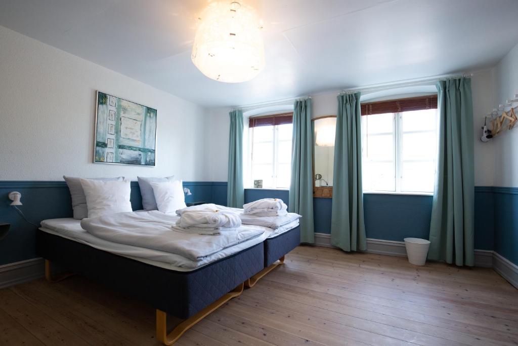 1 dormitorio con 1 cama grande, paredes y ventanas azules en Gæstgiveri Bregninge en Ærøskøbing
