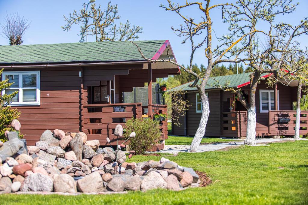 a log cabin with a pile of rocks in front of it at Žaliasis kampas Nameliai Šventojoje in Šventoji