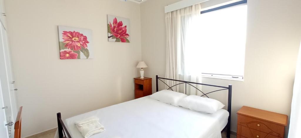 een witte slaapkamer met een bed en een raam bij Hygge Retreat in Preveza