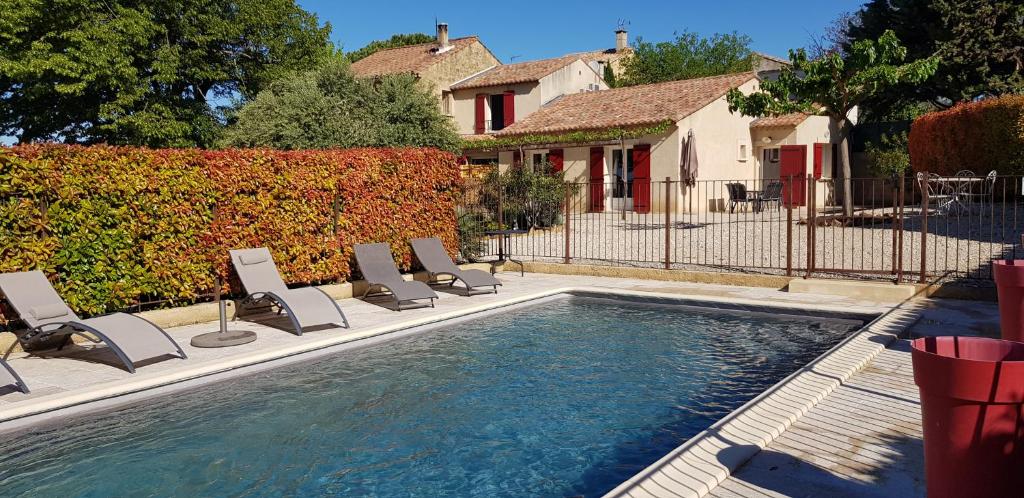 a swimming pool with lounge chairs next to a house at Mas du Tilleul in Beaumes-de-Venise