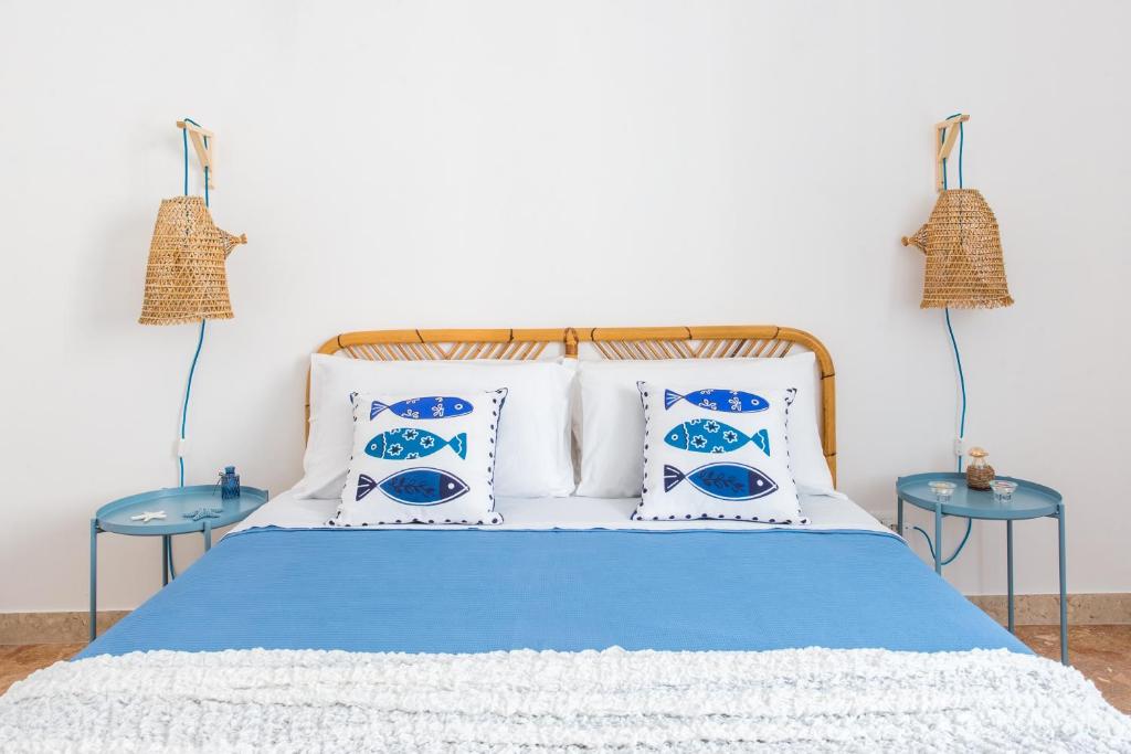 een bed met blauwe en witte kussens en 2 tafels bij Vento di Grecale - a pochi metri dal mare in Santa Flavia