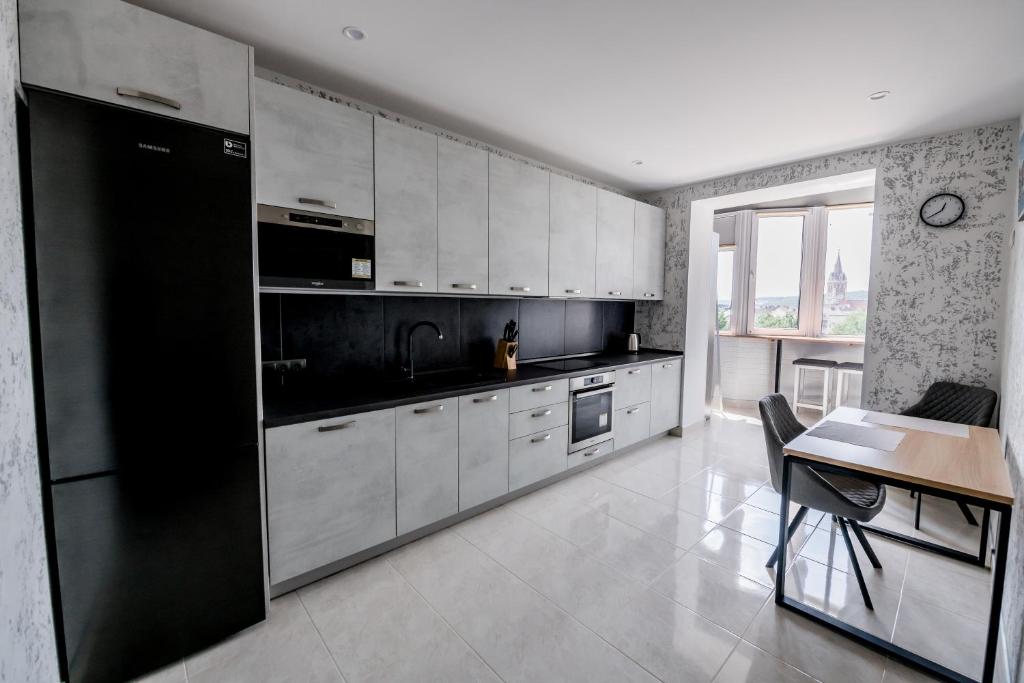 a kitchen with white cabinets and a black refrigerator at Апартаменти OneDay в ценрі Чорткова in Chortkiv