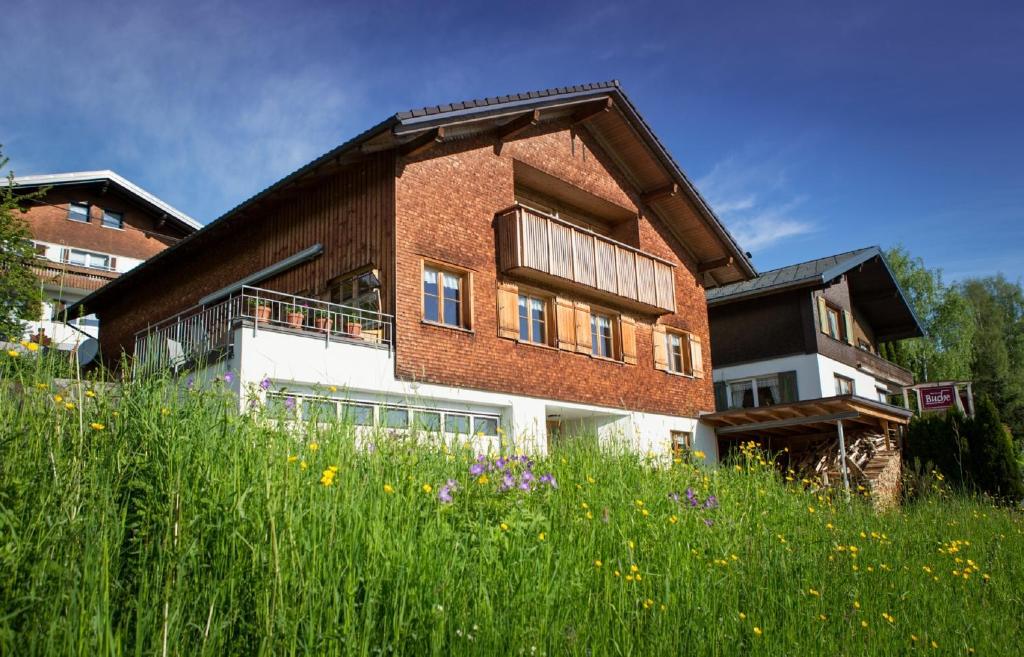 un grand bâtiment en briques avec un champ d'herbe et de fleurs dans l'établissement Haus Elfriede, à Schwarzenberg im Bregenzerwald