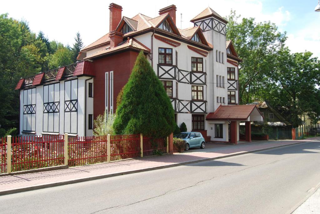 una gran casa blanca y roja con una valla roja en FAMILIJNY Ośrodek Wypoczynkowo - Rehabilitacyjny Krynica Zdrój, en Krynica-Zdrój