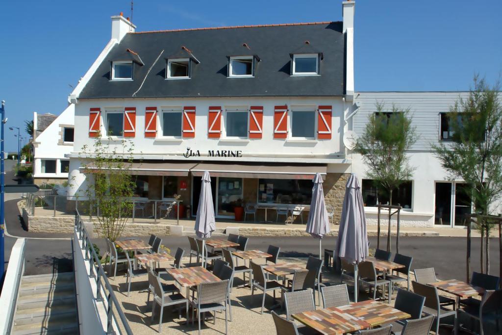 un ristorante con tavoli e sedie di fronte a un edificio di La Marine a Sibiril