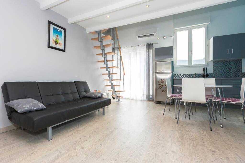 un salon avec un canapé noir et une cuisine dans l'établissement Primavera, à Avignon