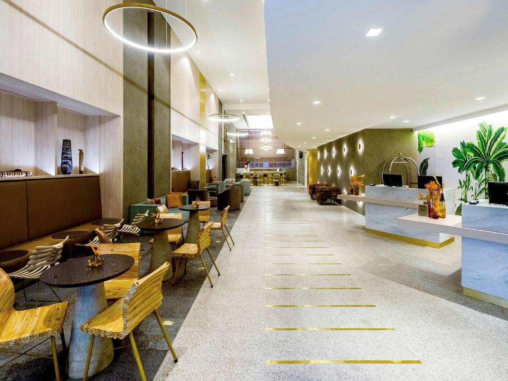 a restaurant with tables and chairs and a lobby at Grand Mercure Sao Paulo Vila Olimpia in Sao Paulo