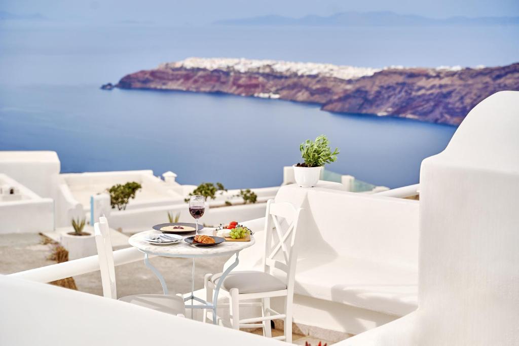 a table and chairs on a balcony with a view of the ocean at Merovigliosso in Imerovigli