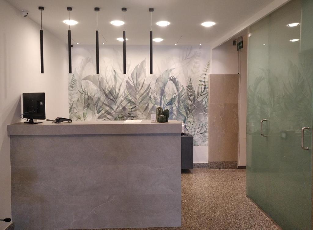 a lobby with a reception desk with a mural of plants at Tea Palace Hotel in Casapulla