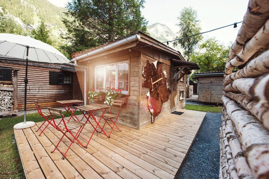 a cabin with a wooden deck with a table and chairs at Camping Jungfrau in Lauterbrunnen