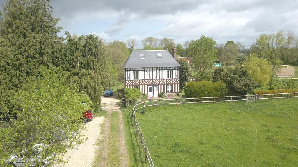 une grande maison dans un champ avec un chemin de terre dans l'établissement Gîte chez Loupi, à Épaignes