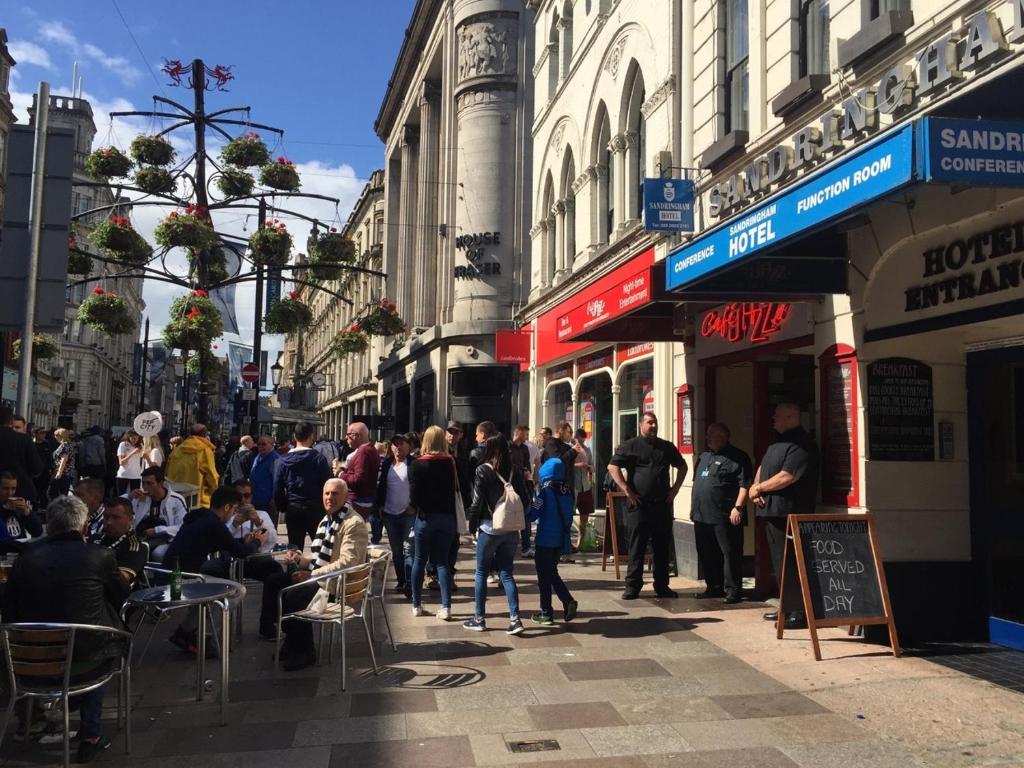 una folla di persone che camminano per una strada trafficata di Cardiff Sandringham Hotel a Cardiff