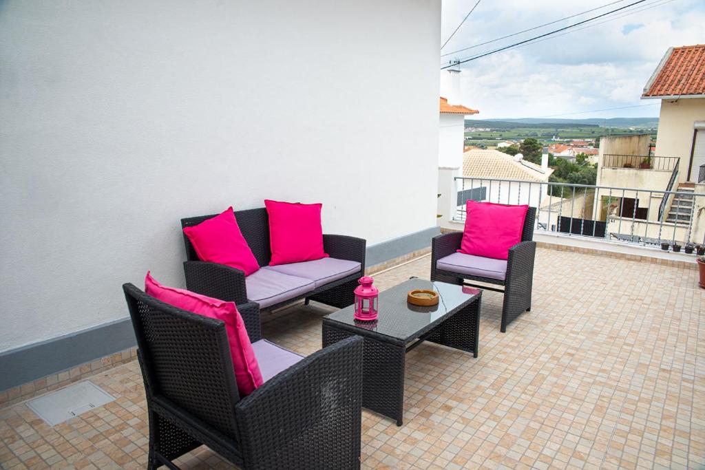 un patio con 2 sillas y una mesa con almohadas rosas en Alojamento das Fontes en Alenquer