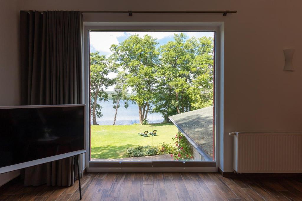 a living room with a large window looking out at a park at Seehotel Lindenhof in Lychen