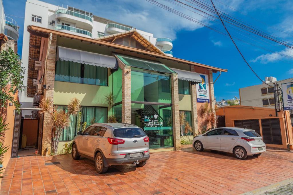 dos coches estacionados frente a un edificio en Pousada Ondas do Forte, en Cabo Frío