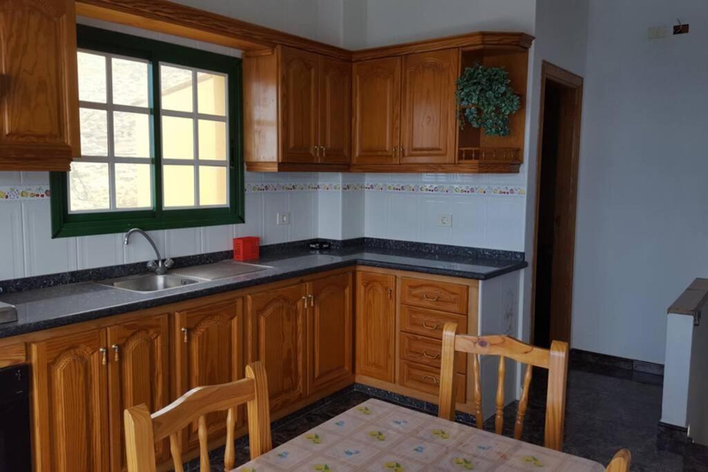 a kitchen with wooden cabinets and a sink and a window at Pozo de las Calcosas - El Hierro in Pozo de las Calcosas
