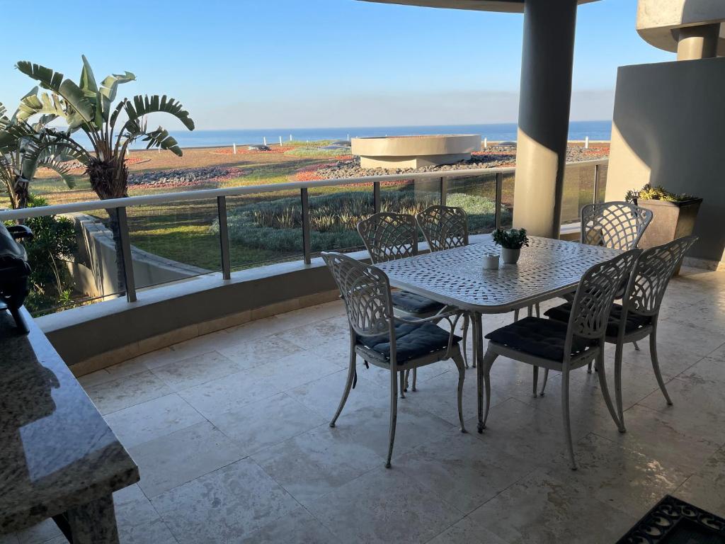 a table and chairs on a balcony with a view of the ocean at Ballito Manor - Manor Gardens 204 - complex generator in Ballito