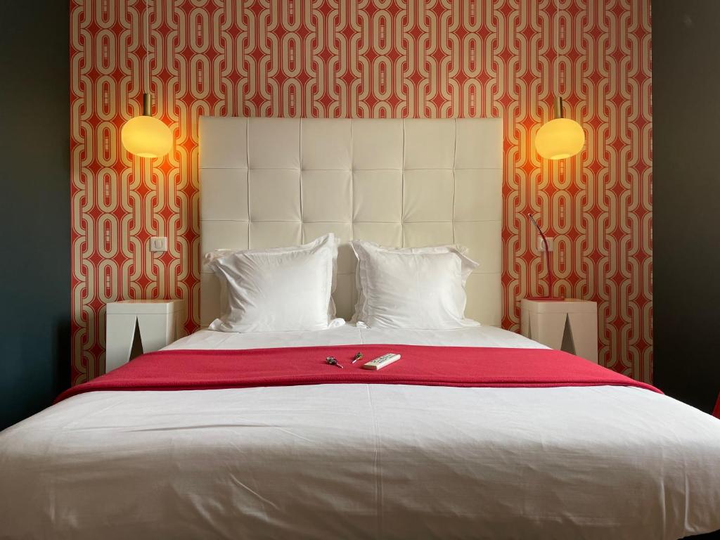 1 dormitorio con 1 cama blanca grande con manta roja en Hôtel Mirano, en Biarritz