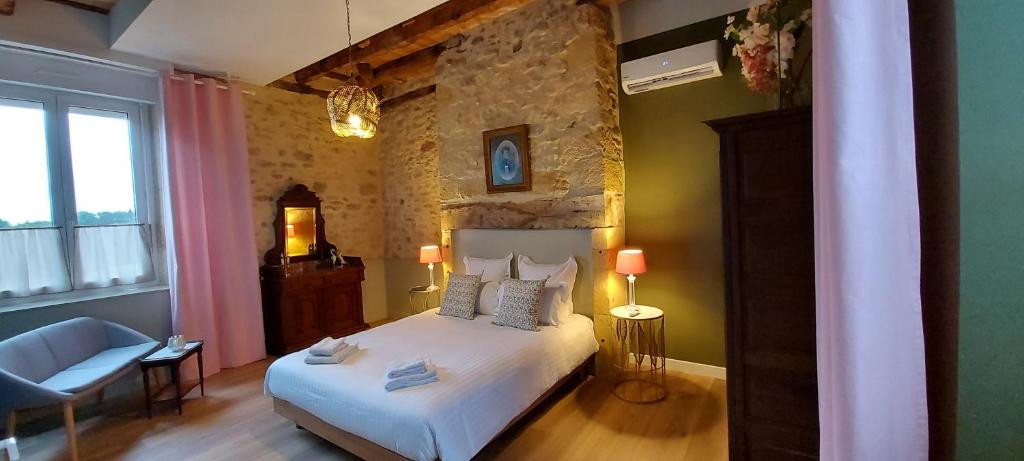 sypialnia z białym łóżkiem i kamienną ścianą w obiekcie Le Clos des Bories w mieście Sarlat-la-Canéda