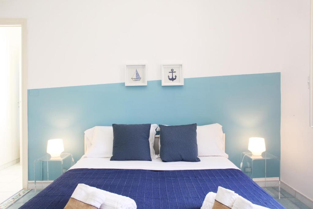 um quarto com uma cama azul e 2 candeeiros em BeachSide Rooms & Suites em San Vito lo Capo