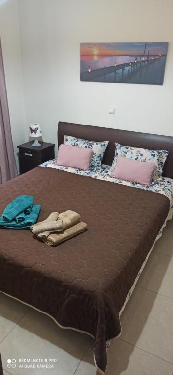 duże łóżko z brązową pościelą i różowymi poduszkami w obiekcie Fotini's Apartment w mieście Néa Péramos