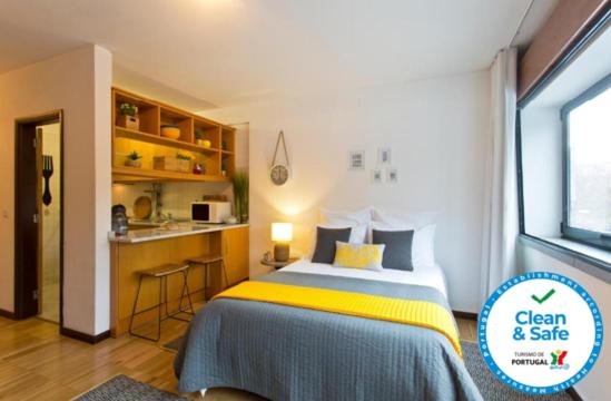 a bedroom with a bed and a small kitchen at JS Apartment in Coimbra