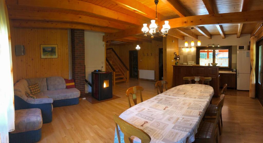 a living room with a large table and a kitchen at Ivola Vendégház in Izvoare