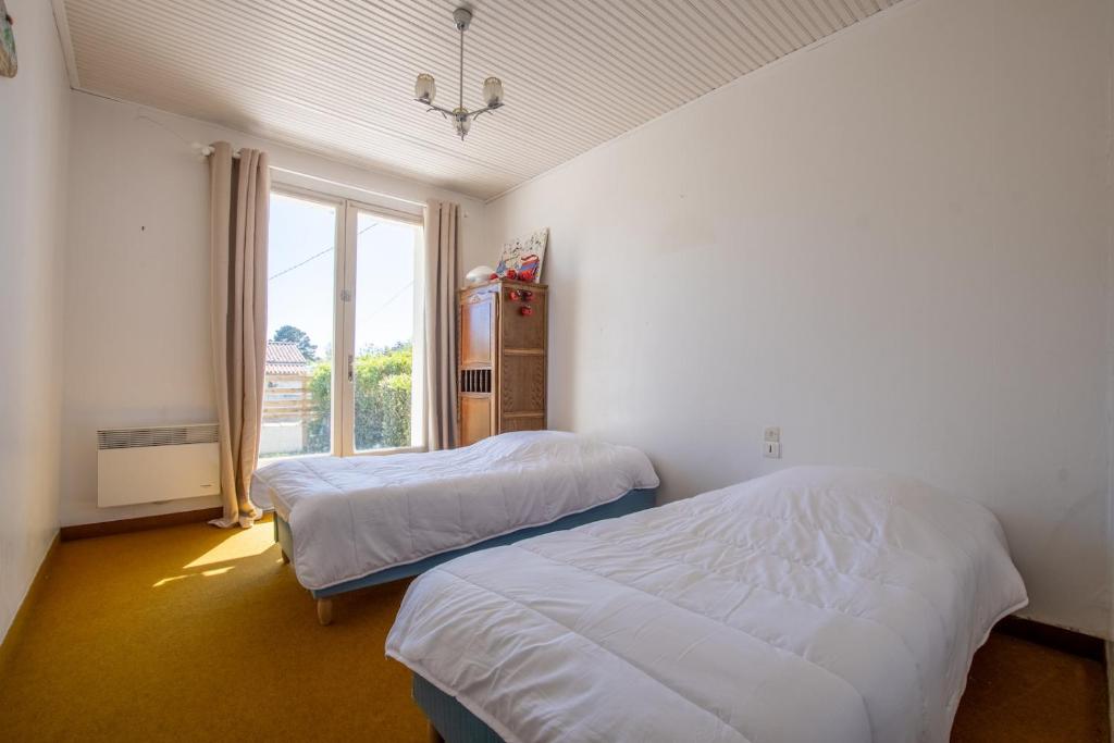 two beds in a room with a window at Nature et decouverte a Brem sur Mer in Brem-sur-Mer