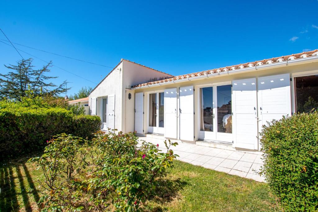 a house with white doors and a yard at Nature et decouverte a Brem sur Mer in Brem-sur-Mer