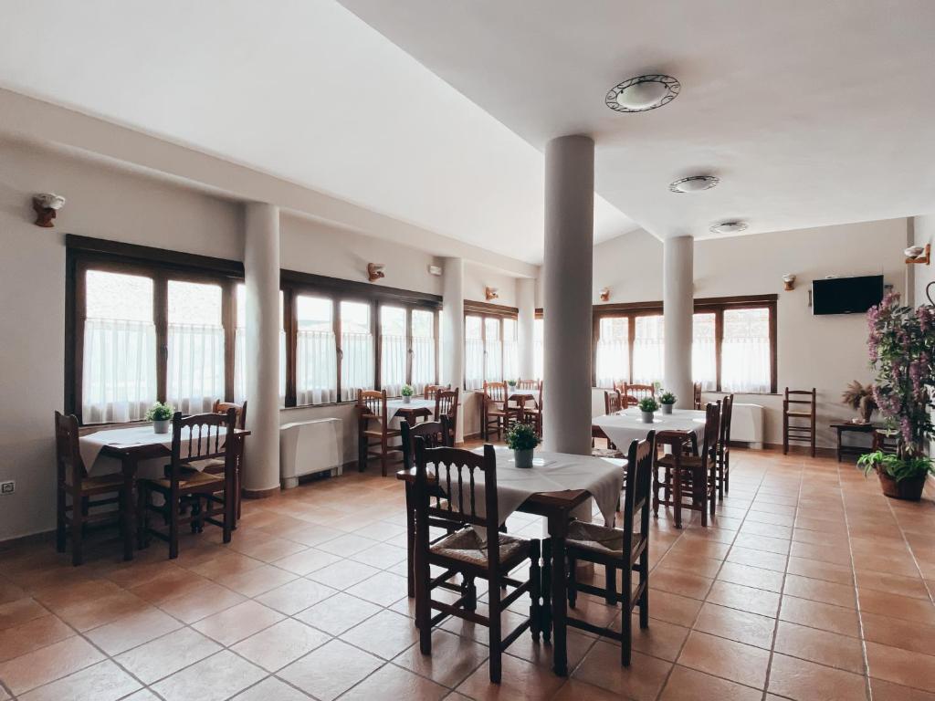 uma sala de jantar com mesas, cadeiras e janelas em Hotel Valdevécar em Albarracín