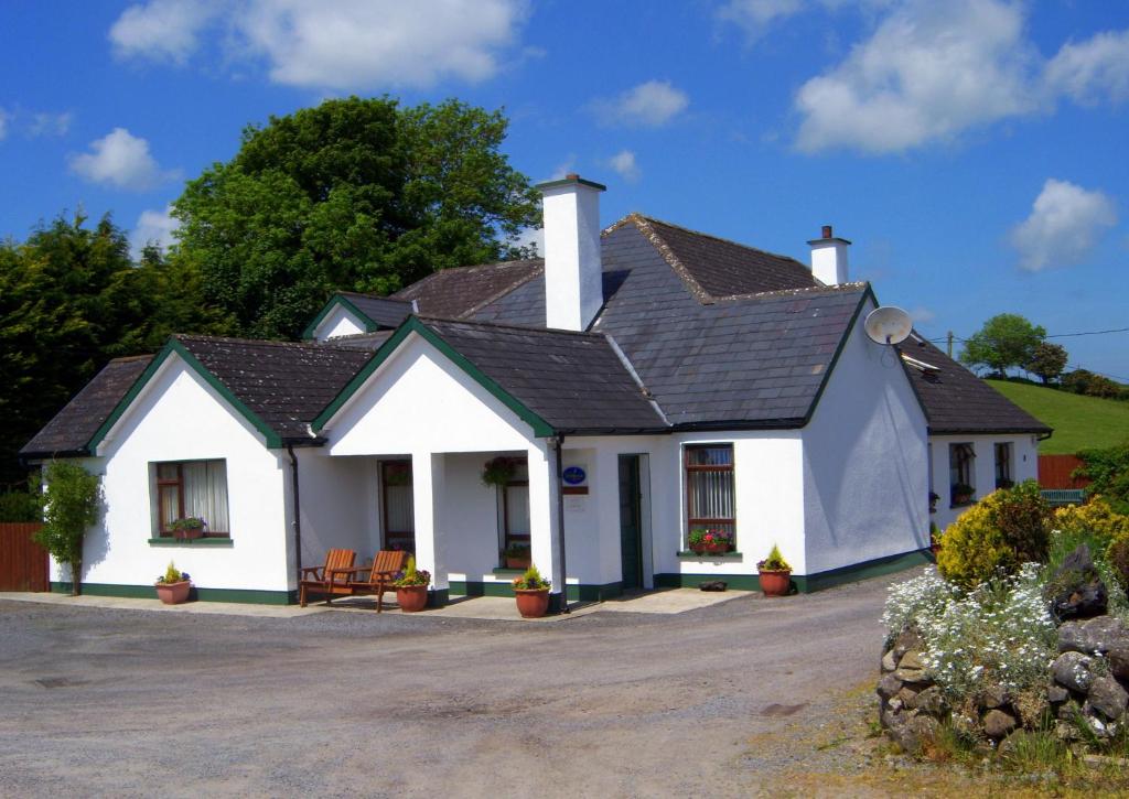 a white house with a black roof at Valley Lodge Room Only Guest House in Claremorris