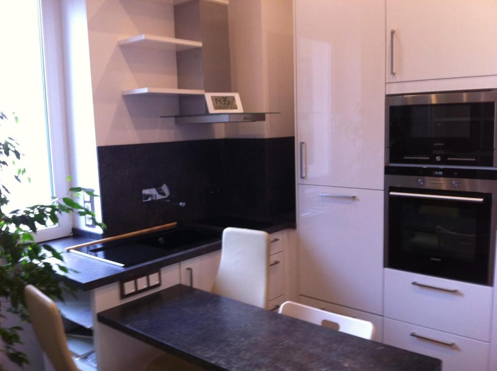 a kitchen with white cabinets and a black counter top at Joanna Apartment - MA Rheinau 3 in Mannheim