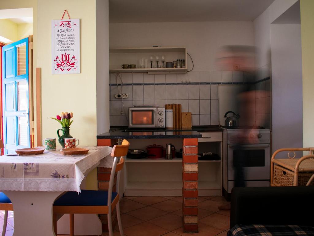 a kitchen with a table and a kitchen with a microwave at Eszti Mama Vendégháza in Cserkeszőlő