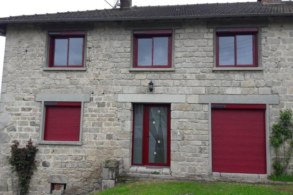 una casa in mattoni con porte e finestre rosse di La maison du cœur a Saint-Moreil