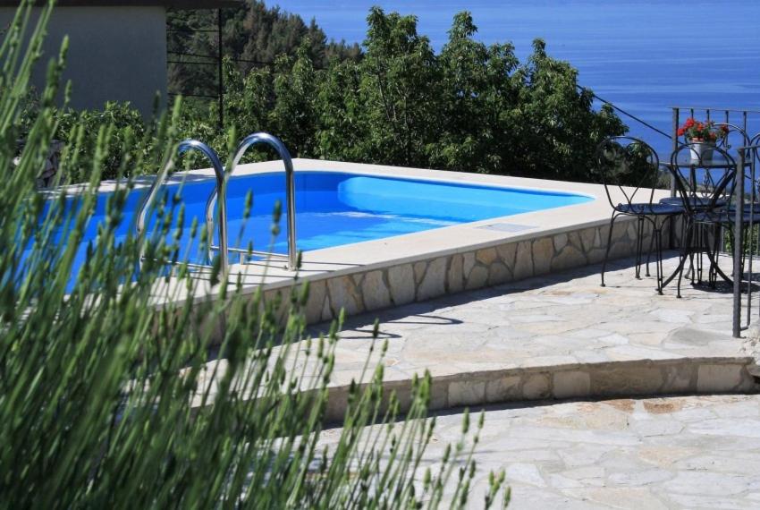 a blue swimming pool with a table and a chair at Villa Marija in Bast