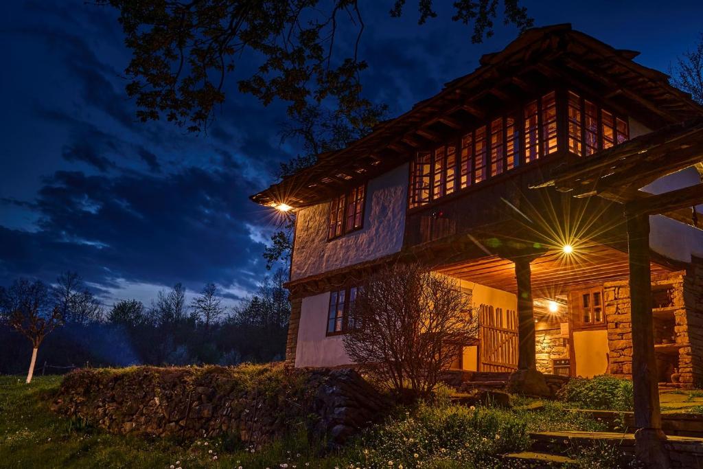 une maison en rondins avec des lumières la nuit dans l'établissement Karashka house, à Apriltsi