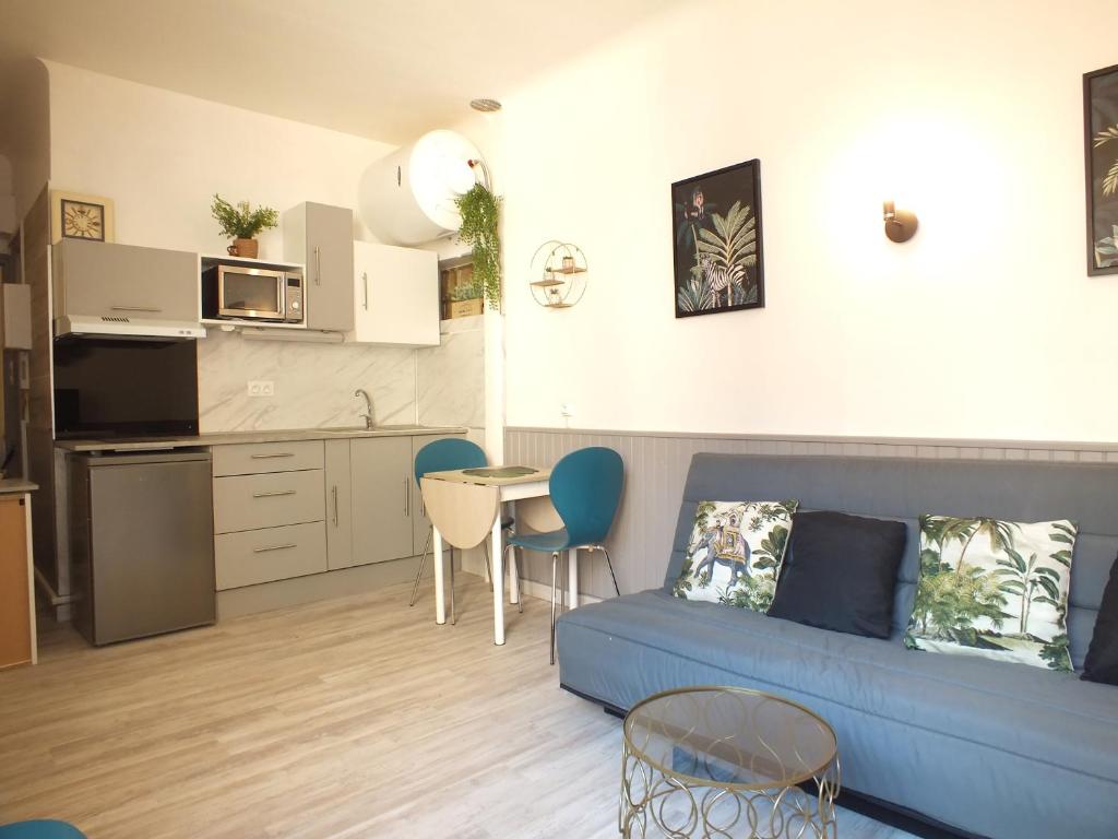 een woonkamer met een blauwe bank en een keuken bij Studio Sirène à 20 m de la plage in Palavas-les-Flots