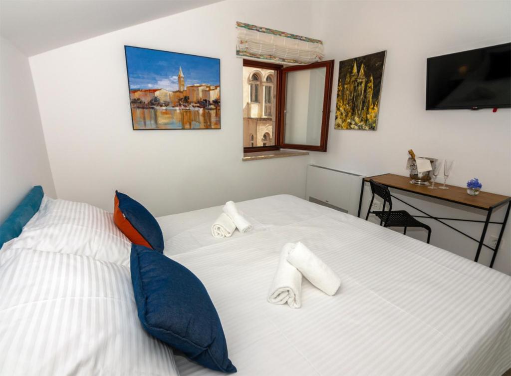 1 dormitorio con 1 cama blanca grande con almohadas azules en B&B Rooms Old Town Rab en Rab