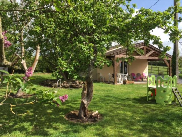 un árbol en un patio al lado de una casa en Gîte de la Grenouille en La Cambe