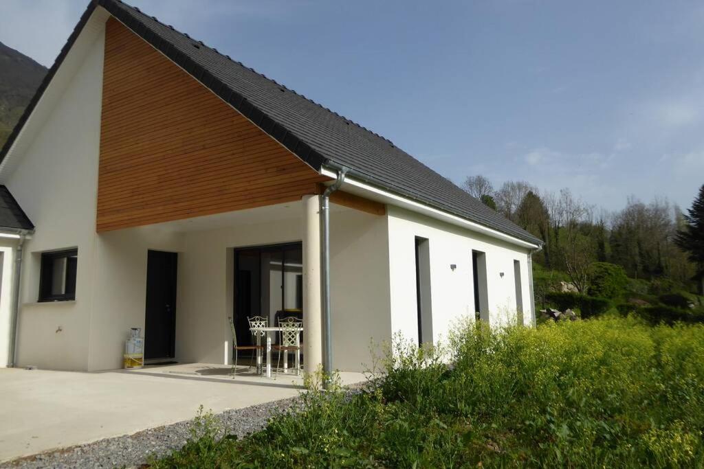 Casa blanca con techo de madera y mesa en Gîte Camdeborde 2 personnes au cœur du village de Laruns, en Laruns