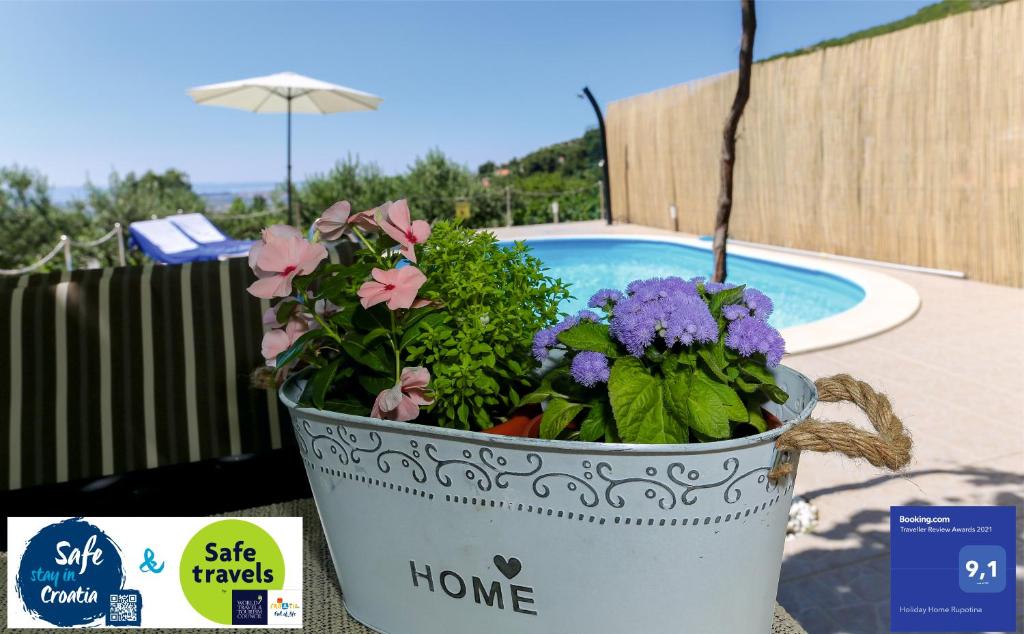 un cubo de flores sentado junto a una piscina en Holiday Home Rupotina with a large yard, pool and a beautiful view, en Solin