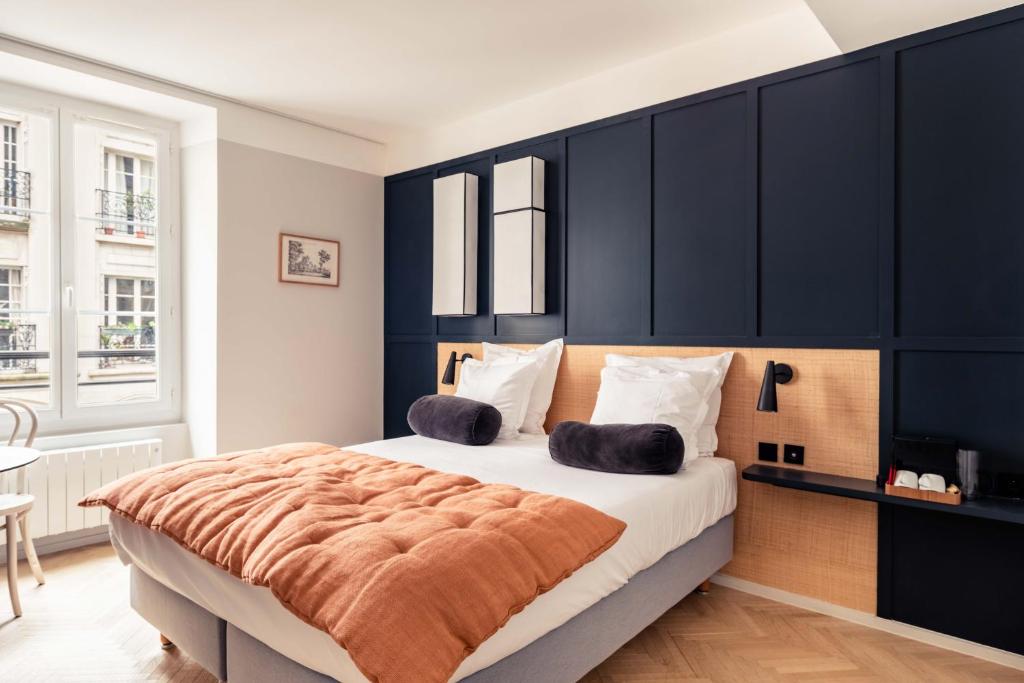 パリにあるHôtel Maison Traversièreの黒い壁のベッドルーム1室(大型ベッド1台付)