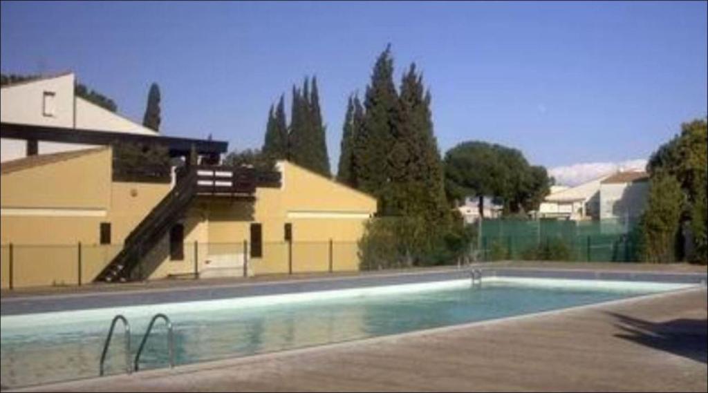 una piscina vacía frente a una casa en Appartement Tennis Village Cap d'Agde en Cap d'Agde