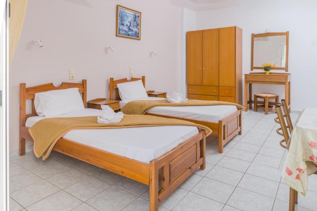 a room with three beds and a mirror at Arsinoi Studios and Apartments in Kalamaki
